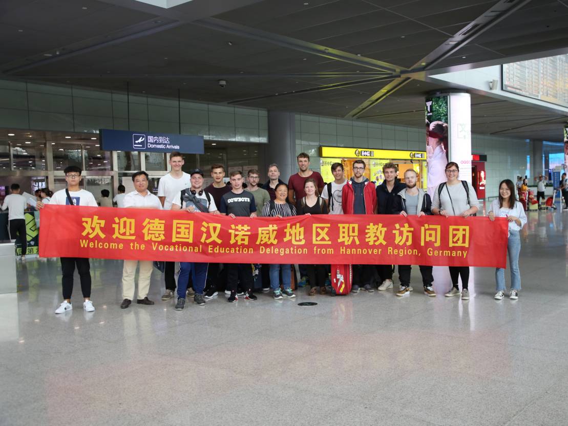 Ein Gruppe von Menschen in einem Flughafen, sie halten gemeinsam ein Banner